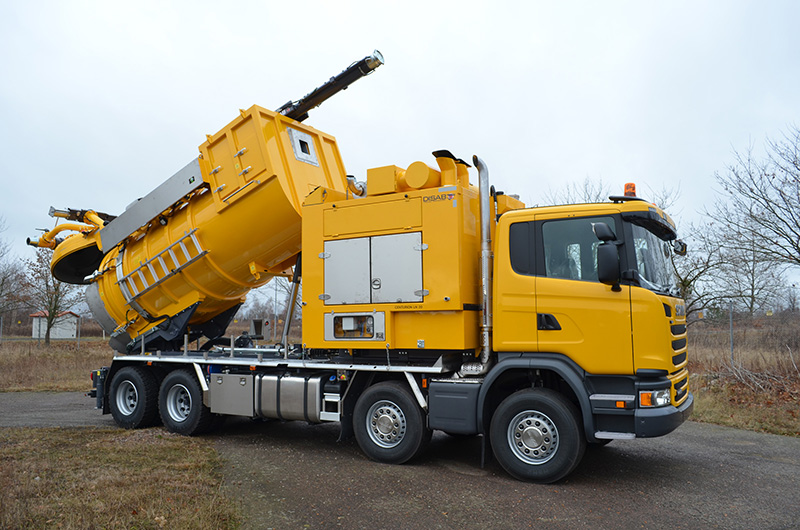Yellow DISAB Centurion™ LN20 vacuum truck with its rear vacuum tank tilted for discharge, illustrating the tipping mechanism used for efficient material emptying in industrial cleaning operations.